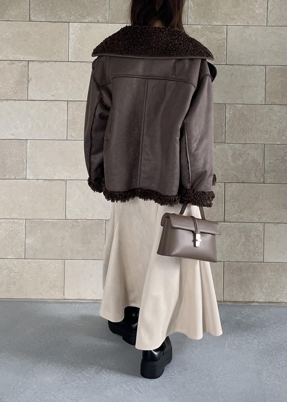 ベージュ系のショルダーバッグ、ブラック系のブーツ、ブラウン系のブルゾンを着用したレディースの秋コーディネートの4枚目の写真