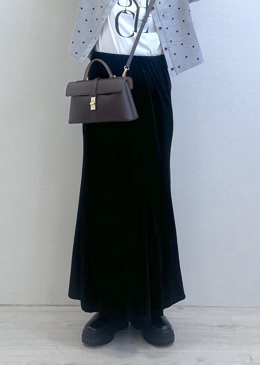 ブラウン系のショルダーバッグ、ブラック系のブーツ、ブラック系のスカートを着用したレディースの秋コーディネートの8枚目の写真