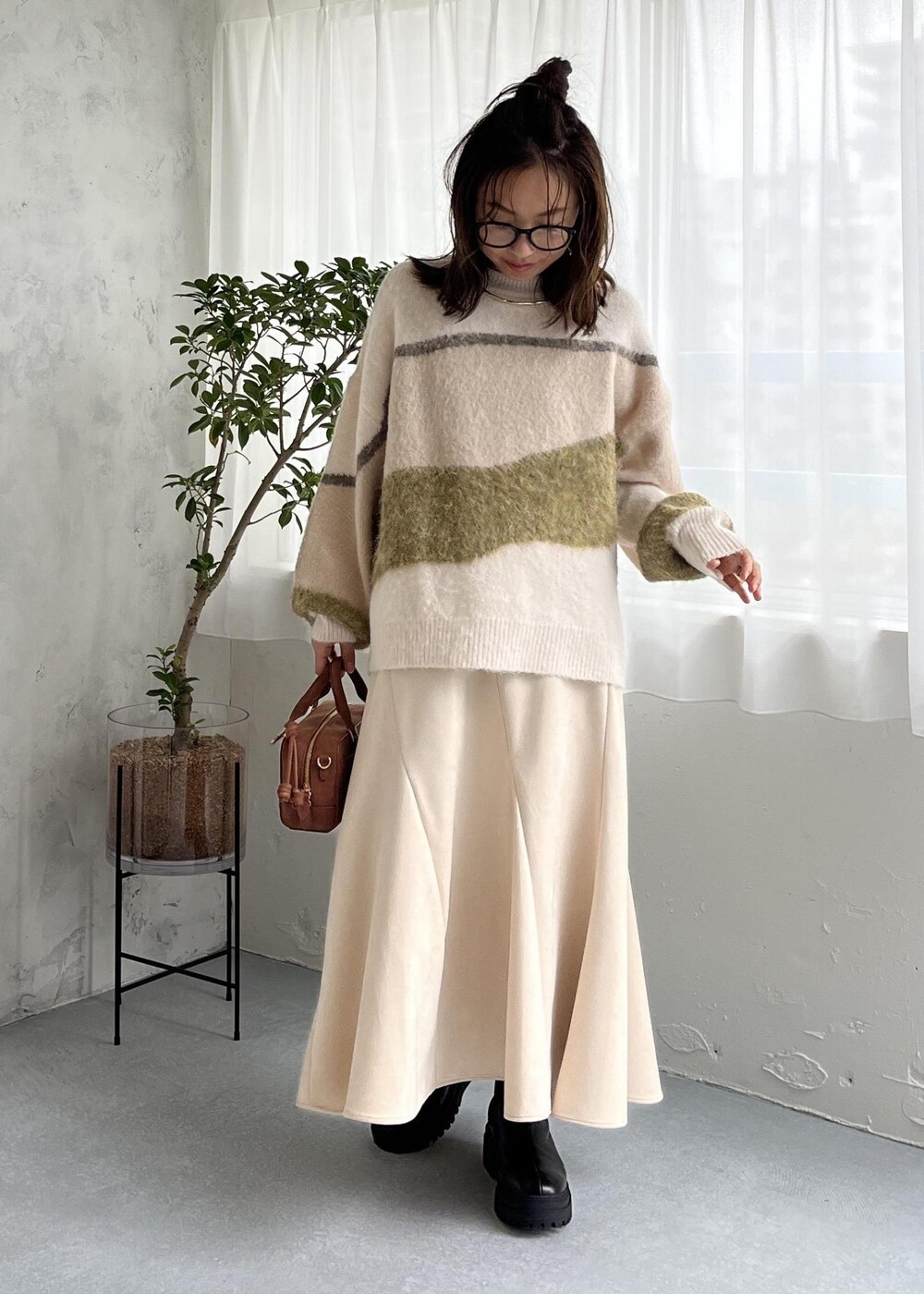 ブラウン系のボストンバッグ、ブラック系のブーツ、ホワイト系のスカートを着用したレディースの秋コーディネートの10枚目の写真