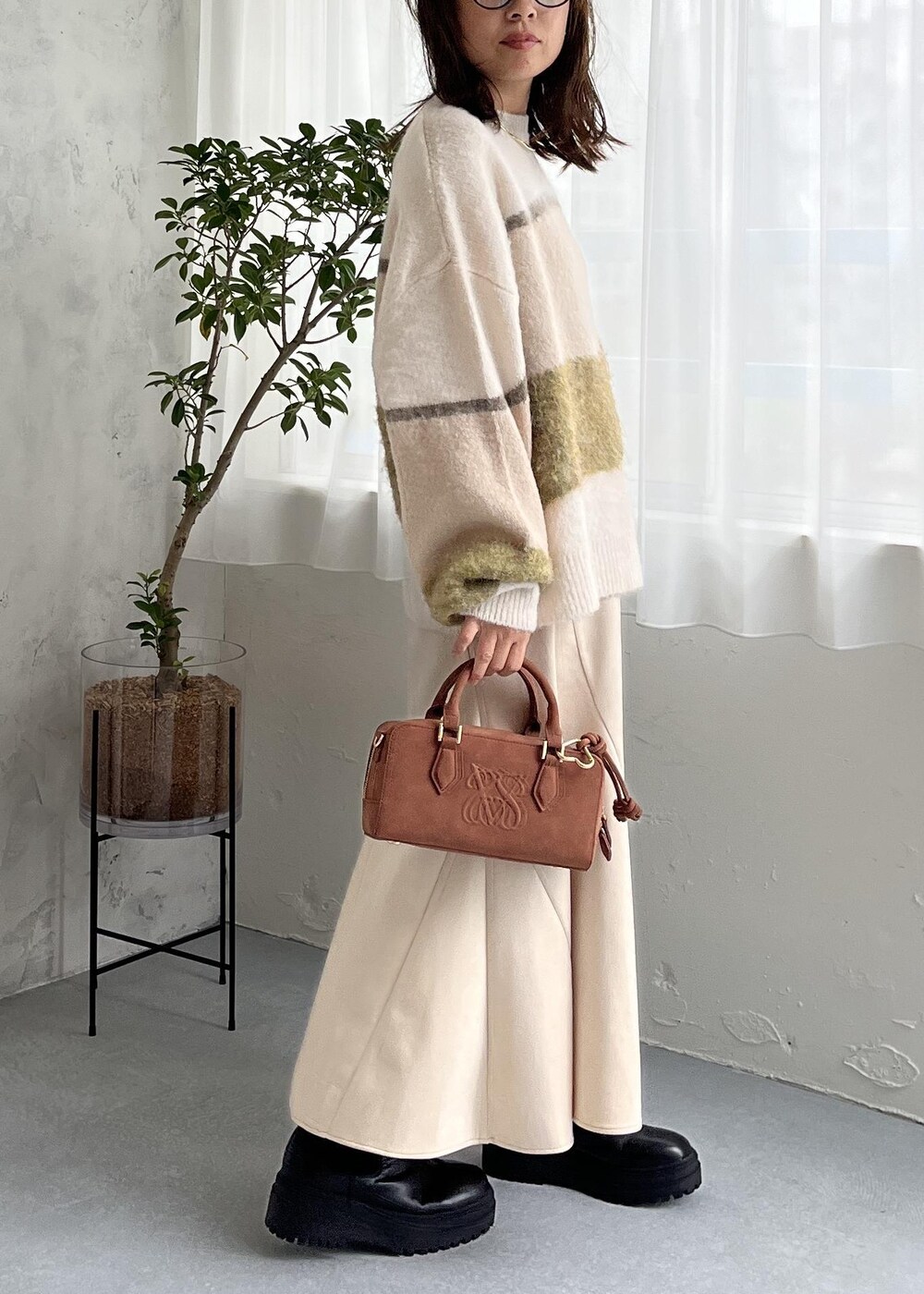 ブラウン系のボストンバッグ、ブラック系のブーツ、ホワイト系のスカートを着用したレディースの秋コーディネートの4枚目の写真