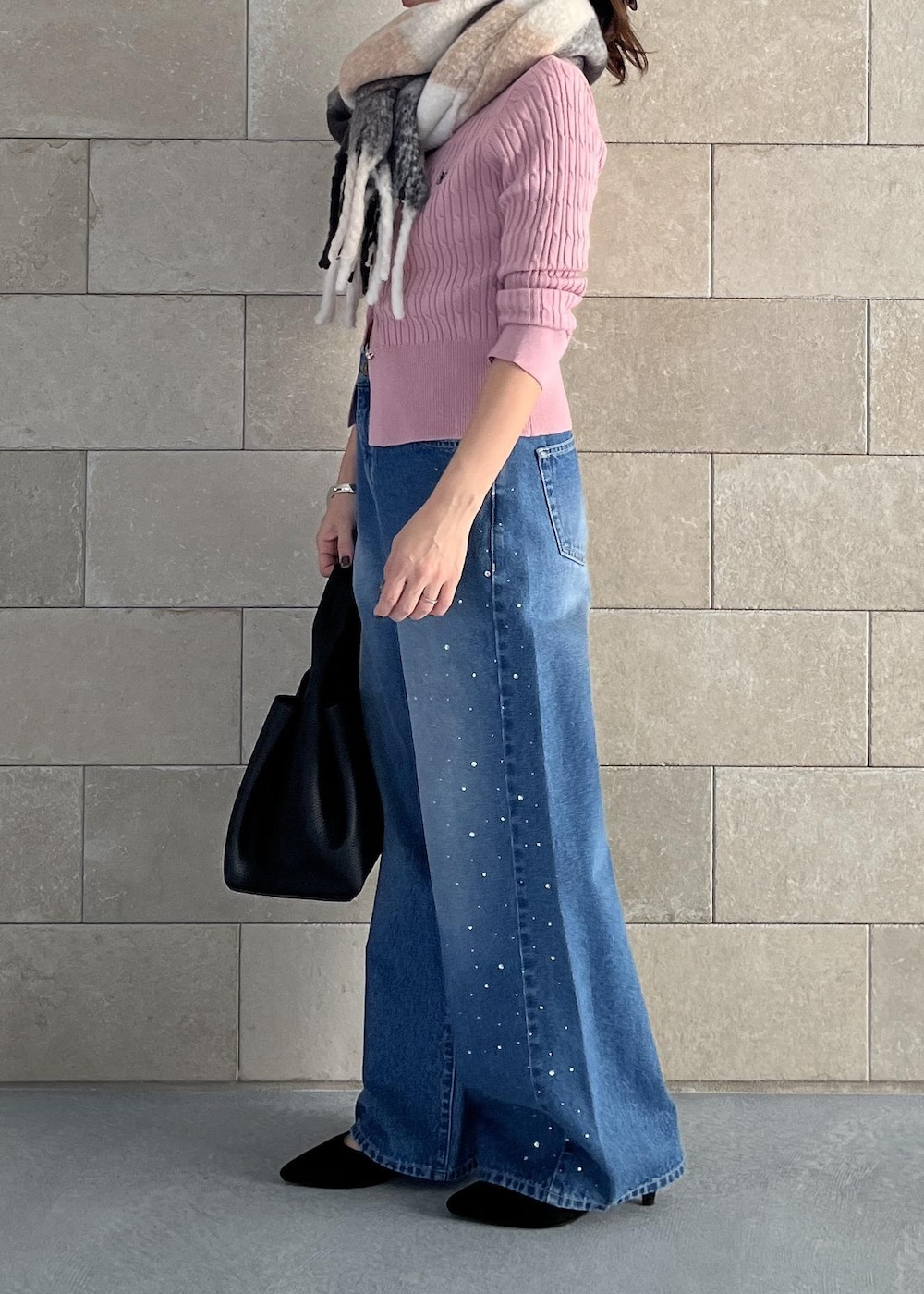 ブラック系のハンドバッグ、ピンク系のカーディガン/ボレロ、ブルー系のデニムパンツを着用したレディースの秋コーディネートの2枚目の写真