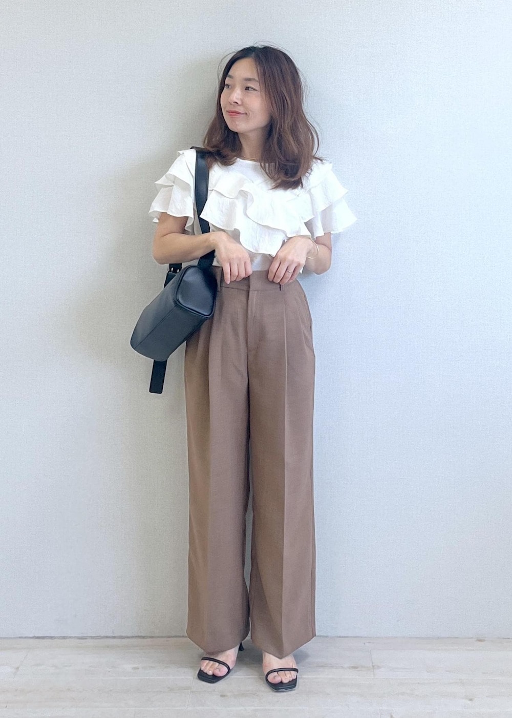 ブラック系のショルダーバッグ、ブラック系のサンダル、ブラウン系のスラックスを着用したレディースの夏コーディネートの7枚目の写真