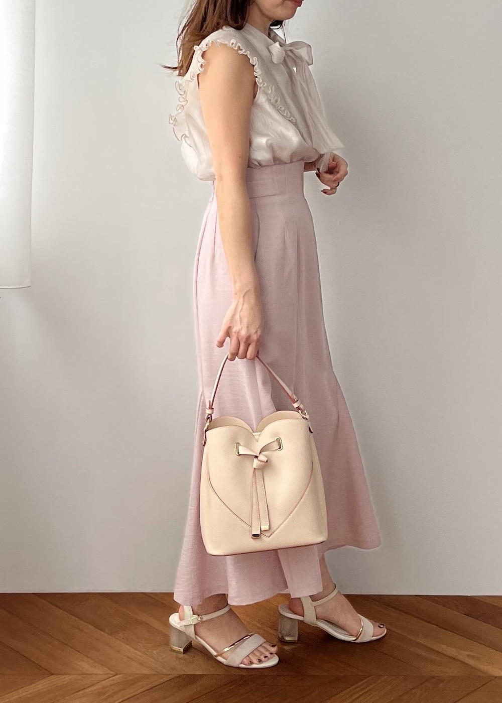 ベージュ系のショルダーバッグ、ピンク系のスカート、ホワイト系のサンダルを着用したレディースの春コーディネートの3枚目の写真