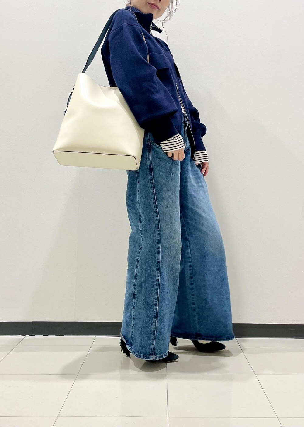 ホワイト系のニット/セーター、ブルー系のカーディガン/ボレロ、ブルー系のデニムパンツを着用したレディースの冬コーディネートの2枚目の写真