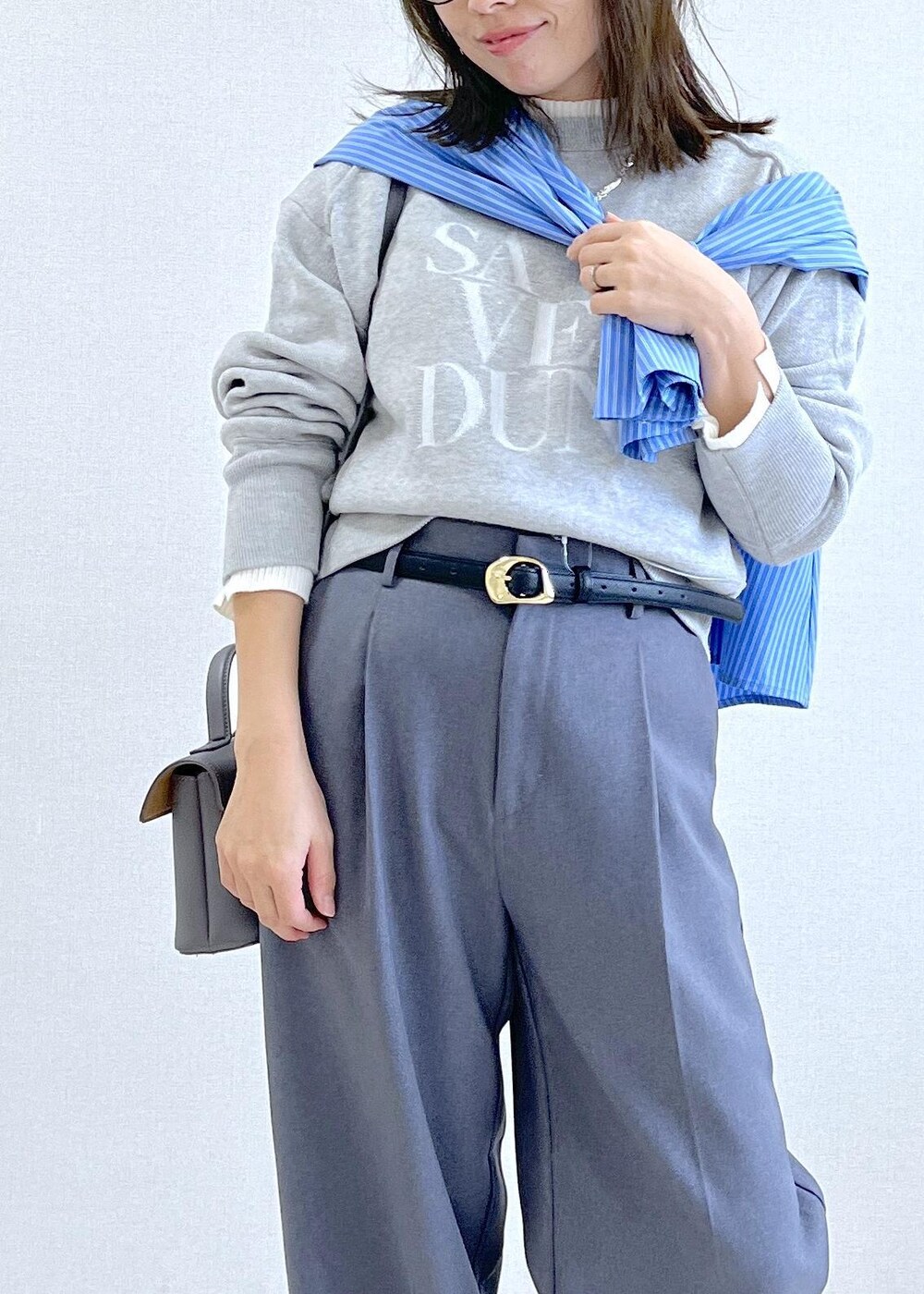 グレー系のショルダーバッグ、グレー系のスラックス、ブルー系のシャツ/ブラウスを着用したレディースの秋コーディネートの2枚目の写真