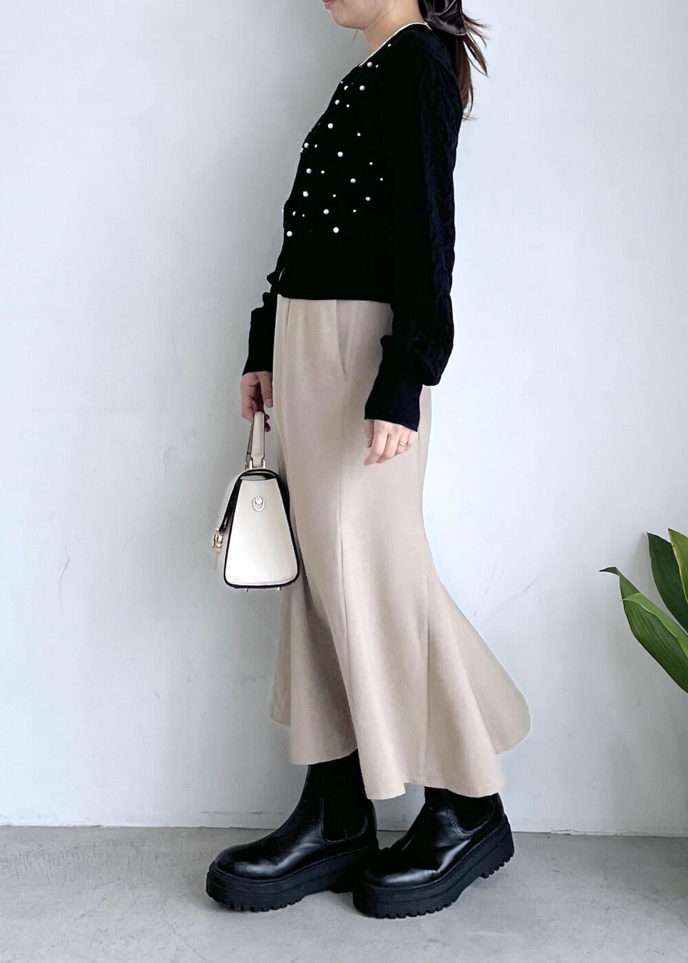 ブラック系のブーツ、ベージュ系のスカート、ブラック系のカーディガン/ボレロを着用したレディースの秋コーディネートの2枚目の写真