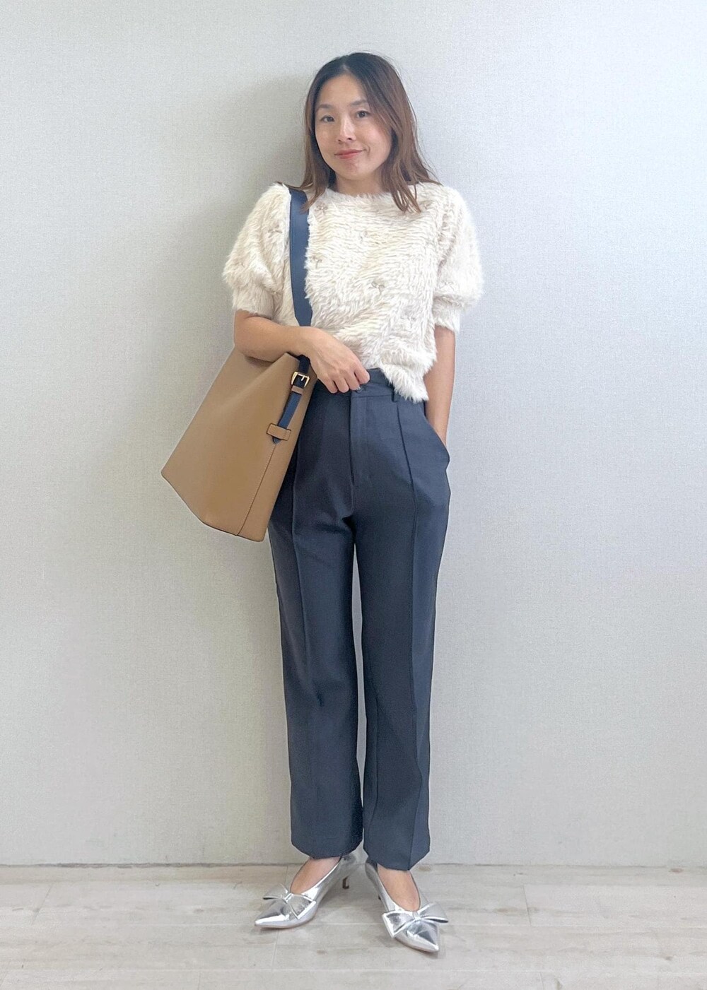 シルバー系のパンプス、イエロー系のショルダーバッグ、ホワイト系のニット/セーターを着用したレディースの秋コーディネートの7枚目の写真