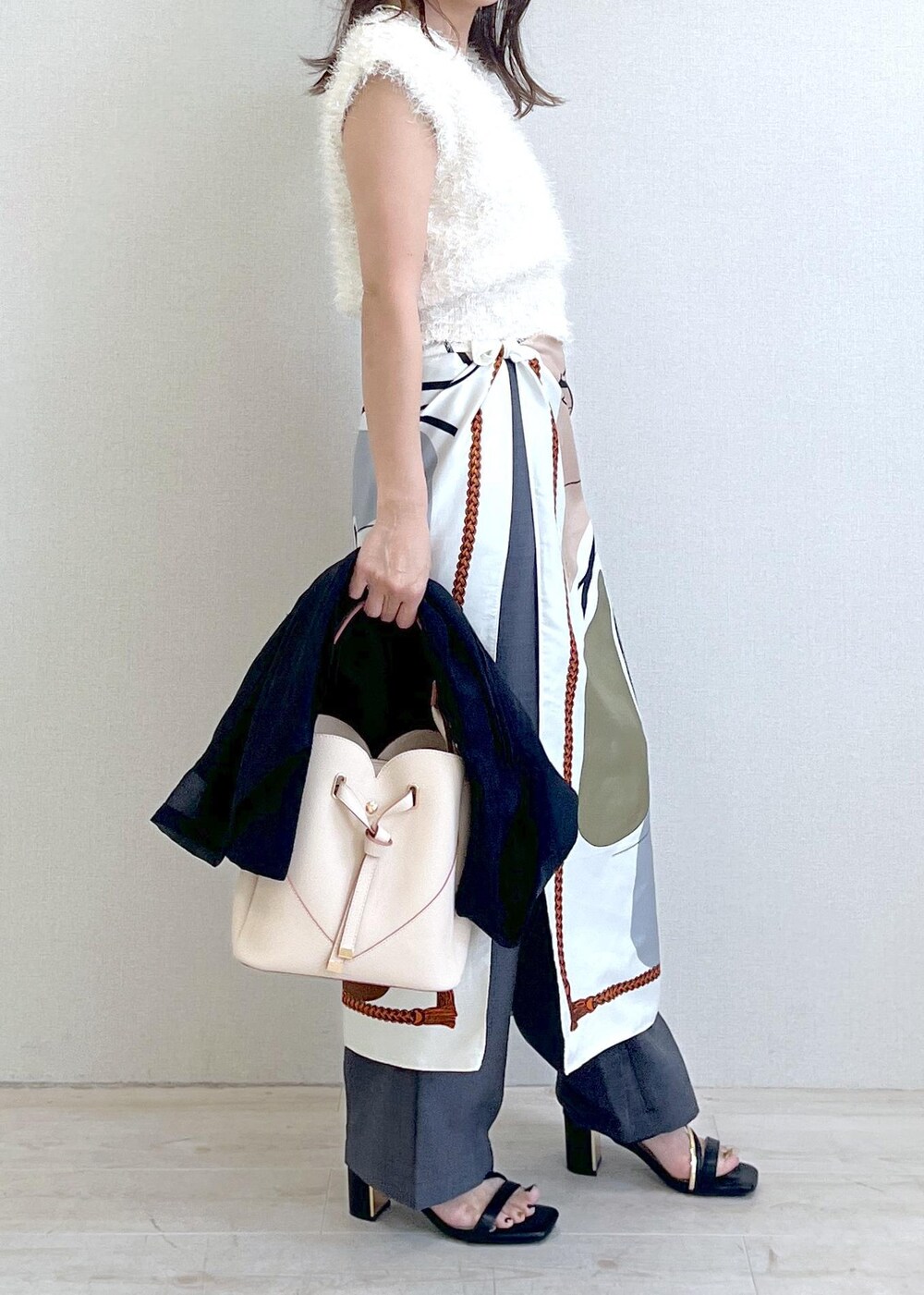 ベージュ系のショルダーバッグ、ブラック系のサンダル、ブラック系のテーラードジャケットを着用したレディースの夏コーディネートの3枚目の写真