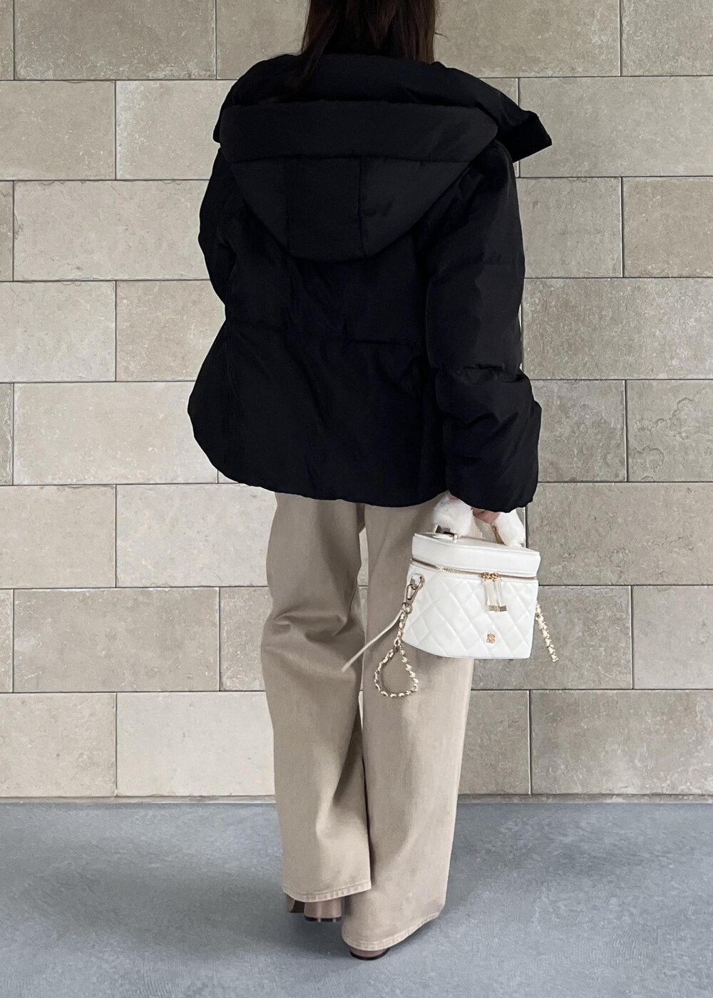 ブラック系のダウンジャケット/コート、ベージュ系のブーツ、ホワイト系のハンドバッグを着用したレディースの秋コーディネートの7枚目の写真