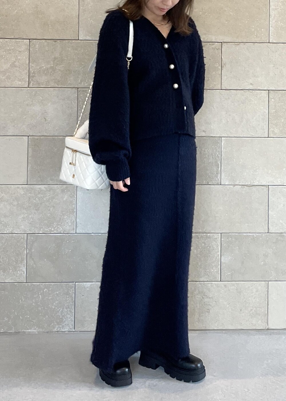 ブラック系のブーツ、ホワイト系のハンドバッグ、ブルー系のスカートを着用したレディースの秋コーディネートの9枚目の写真