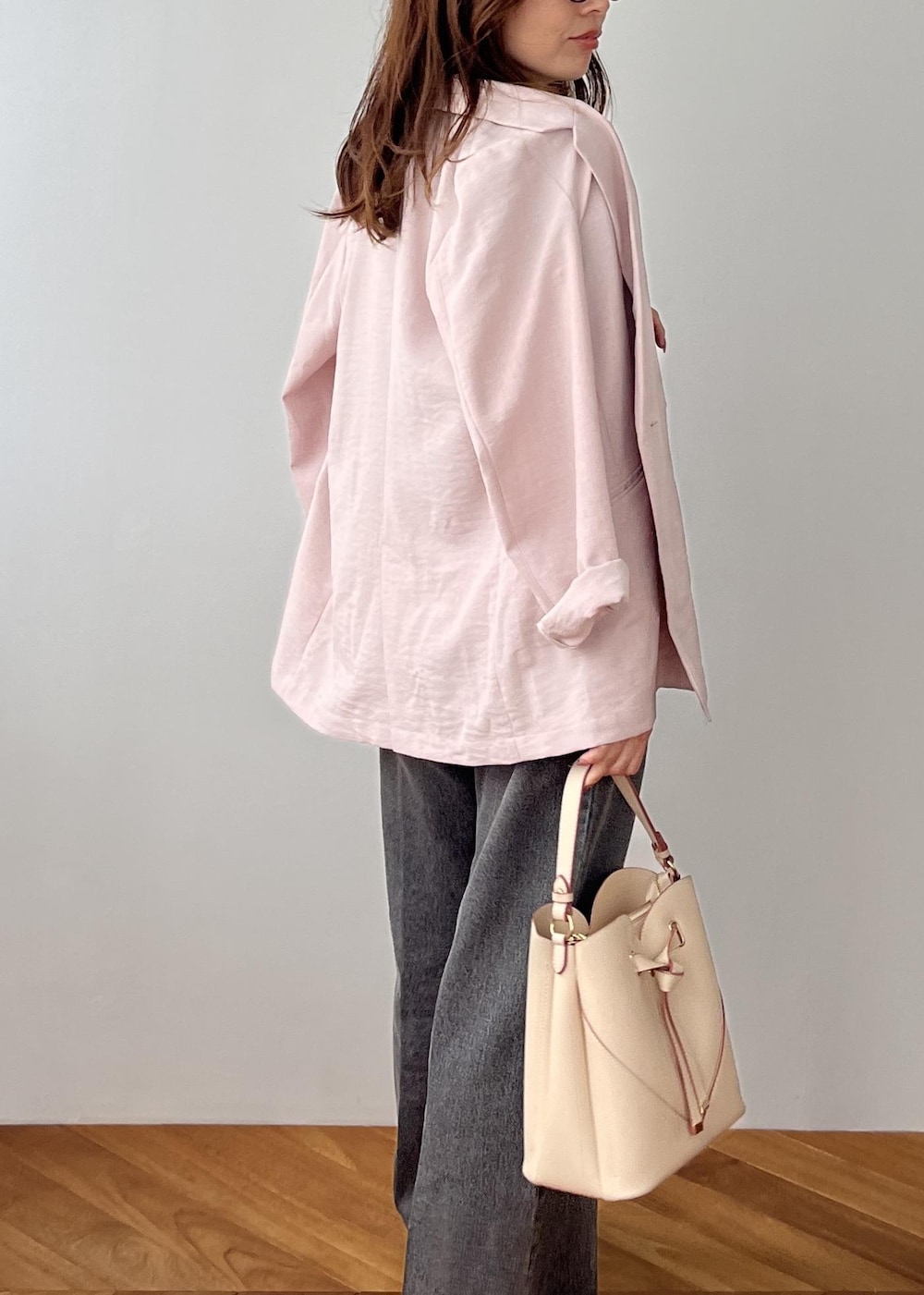 ベージュ系のショルダーバッグ、ピンク系のテーラードジャケット、グレー系のポロシャツを着用したレディースの春コーディネートの7枚目の写真