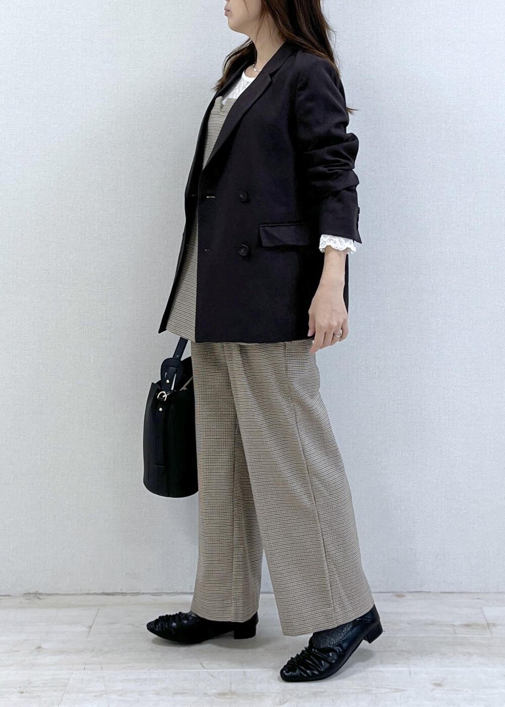 ベージュ系のスラックス、ブラウン系のテーラードジャケット、ベージュ系のキャミソールを着用したレディースの秋コーディネートの4枚目の写真