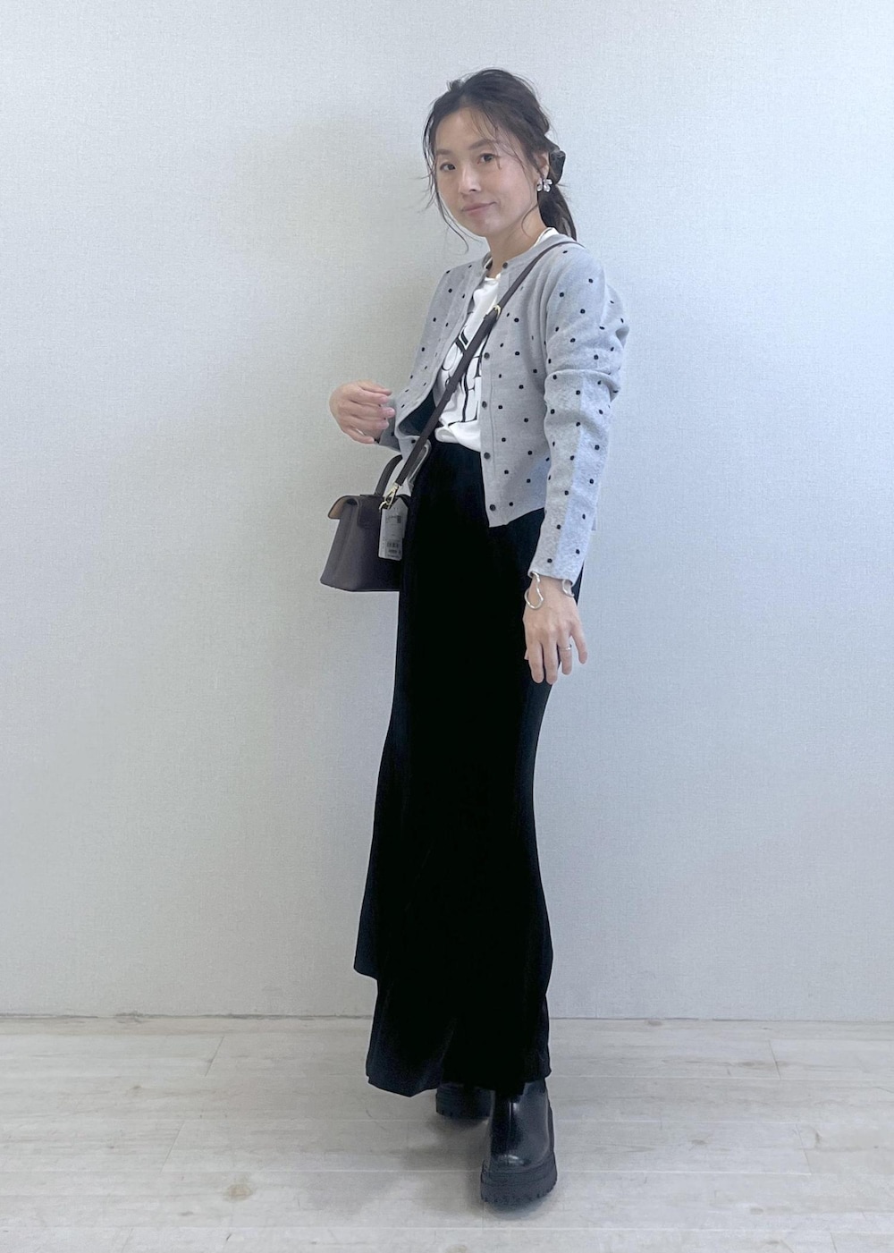 ブラウン系のショルダーバッグ、ブラック系のブーツ、ブラック系のスカートを着用したレディースの秋コーディネートの9枚目の写真