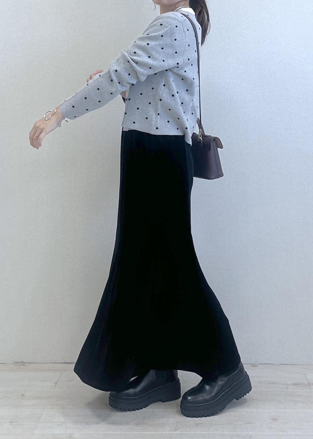 ブラウン系のショルダーバッグ、ブラック系のブーツ、ブラック系のスカートを着用したレディースの秋コーディネートの3枚目の写真