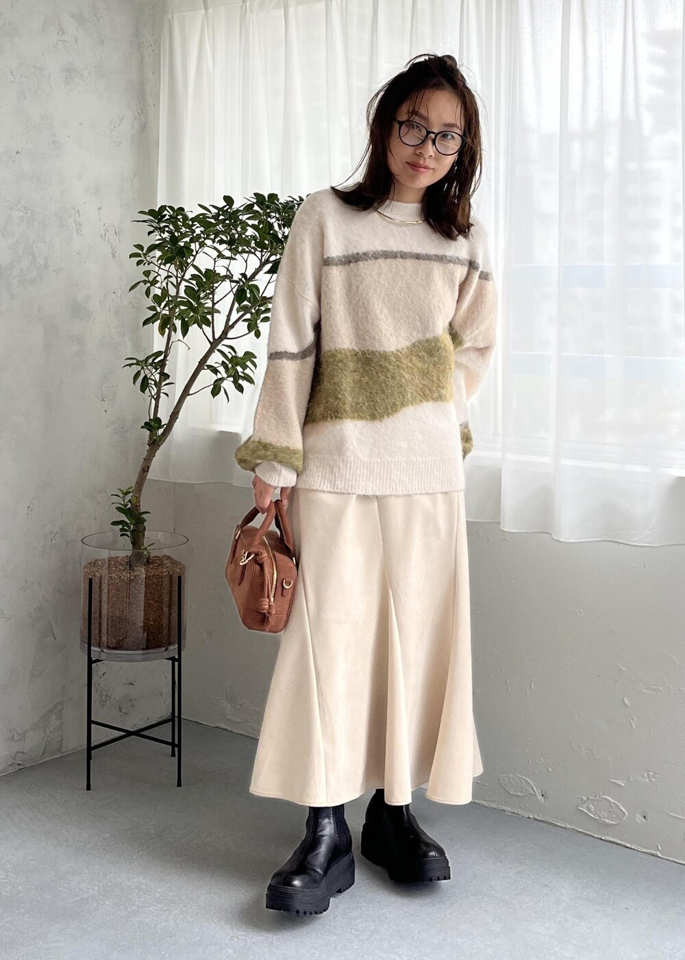 ブラウン系のボストンバッグ、ブラック系のブーツ、ホワイト系のスカートを着用したレディースの秋コーディネートの8枚目の写真