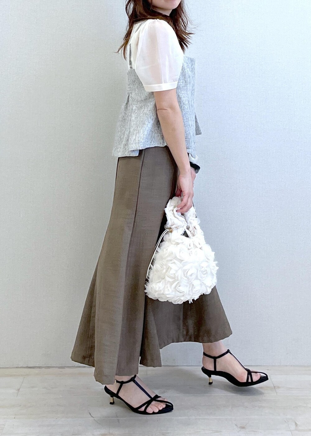 ブラック系のサンダル、ホワイト系のハンドバッグ、グリーン系のスカートを着用したレディースの春コーディネートの3枚目の写真