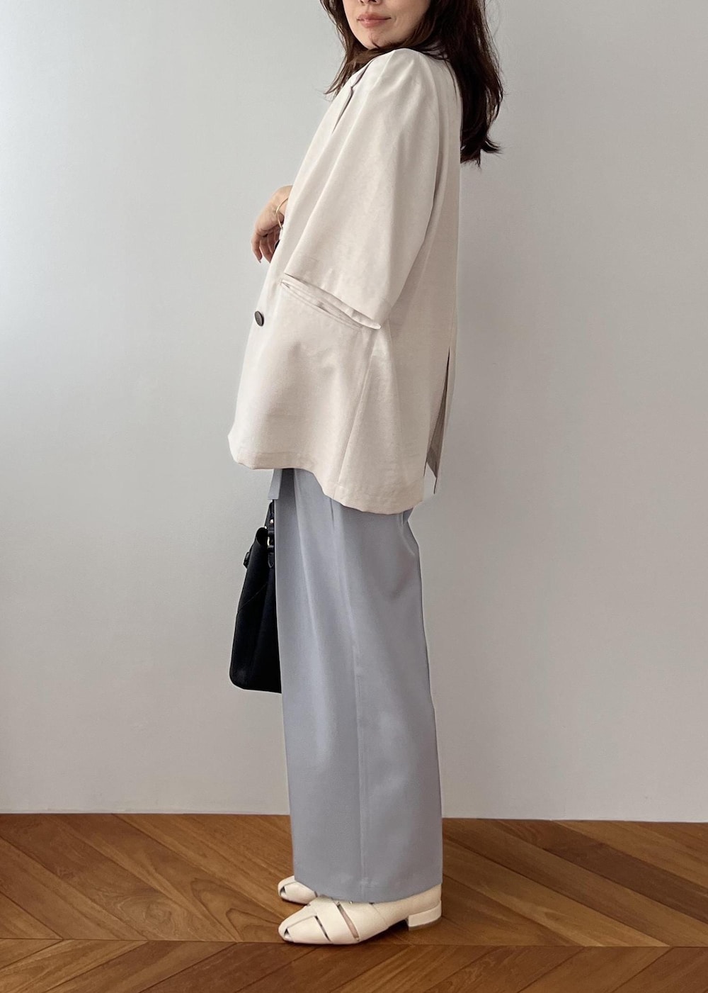 ブラック系のショルダーバッグ、ホワイト系のパンプス、ブルー系のその他パンツを着用したレディースの春コーディネートの2枚目の写真