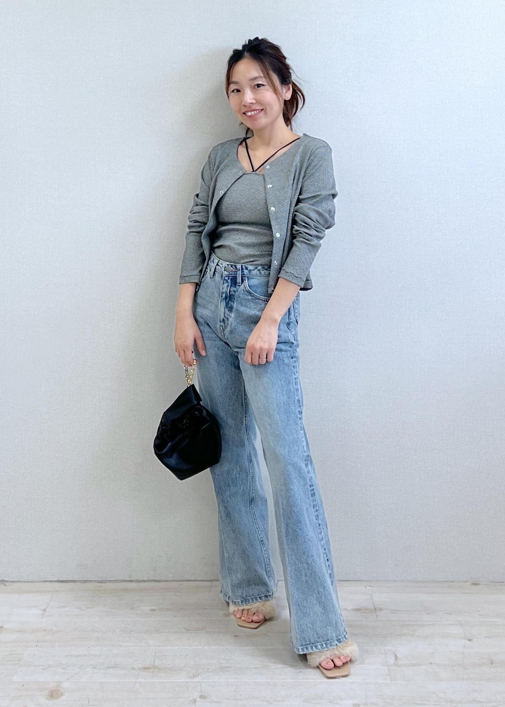 ベージュ系のドレスシューズ、ブラック系のアンサンブル、ブルー系のデニムパンツを着用したレディースの秋コーディネートの2枚目の写真