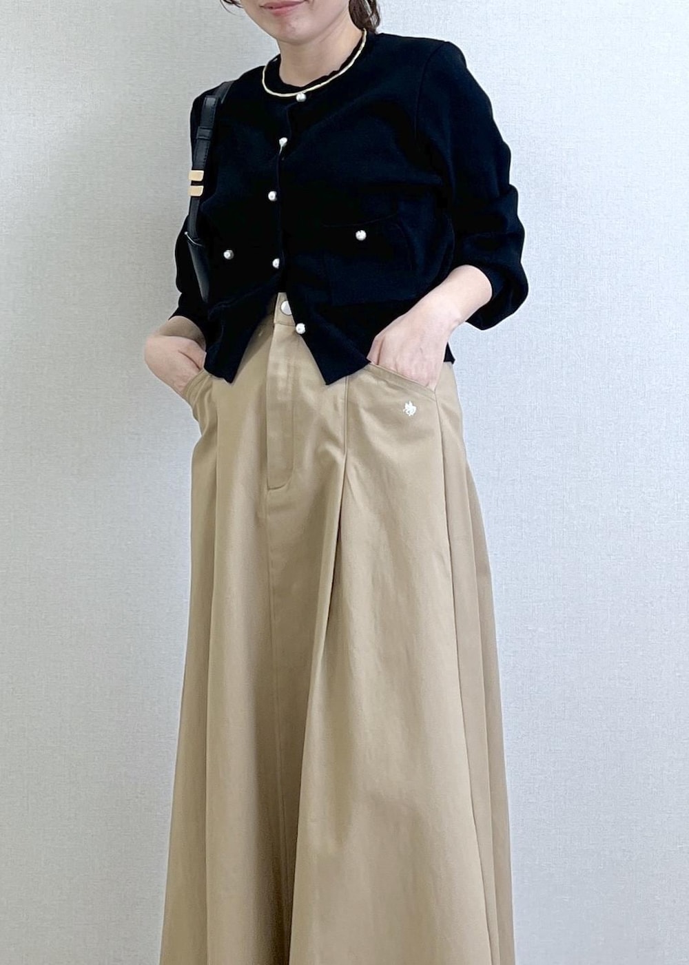 ブラック系のショルダーバッグ、ブラック系のカーディガン/ボレロ、ベージュ系のスカートを着用したレディースの春コーディネートの5枚目の写真