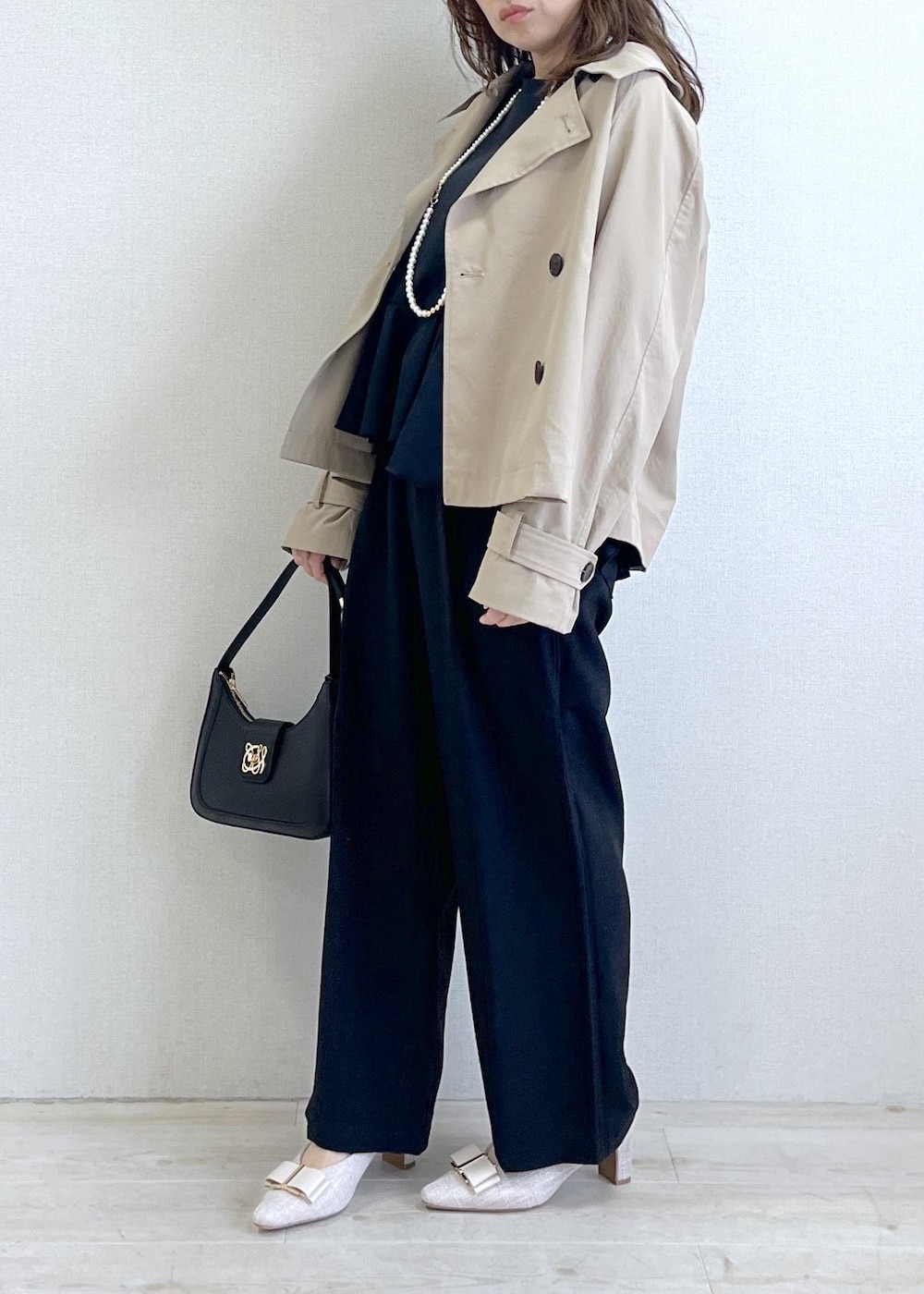 ブラック系のショルダーバッグ、ベージュ系のパンプス、ベージュ系のトレンチコートを着用したレディースの春コーディネートの2枚目の写真