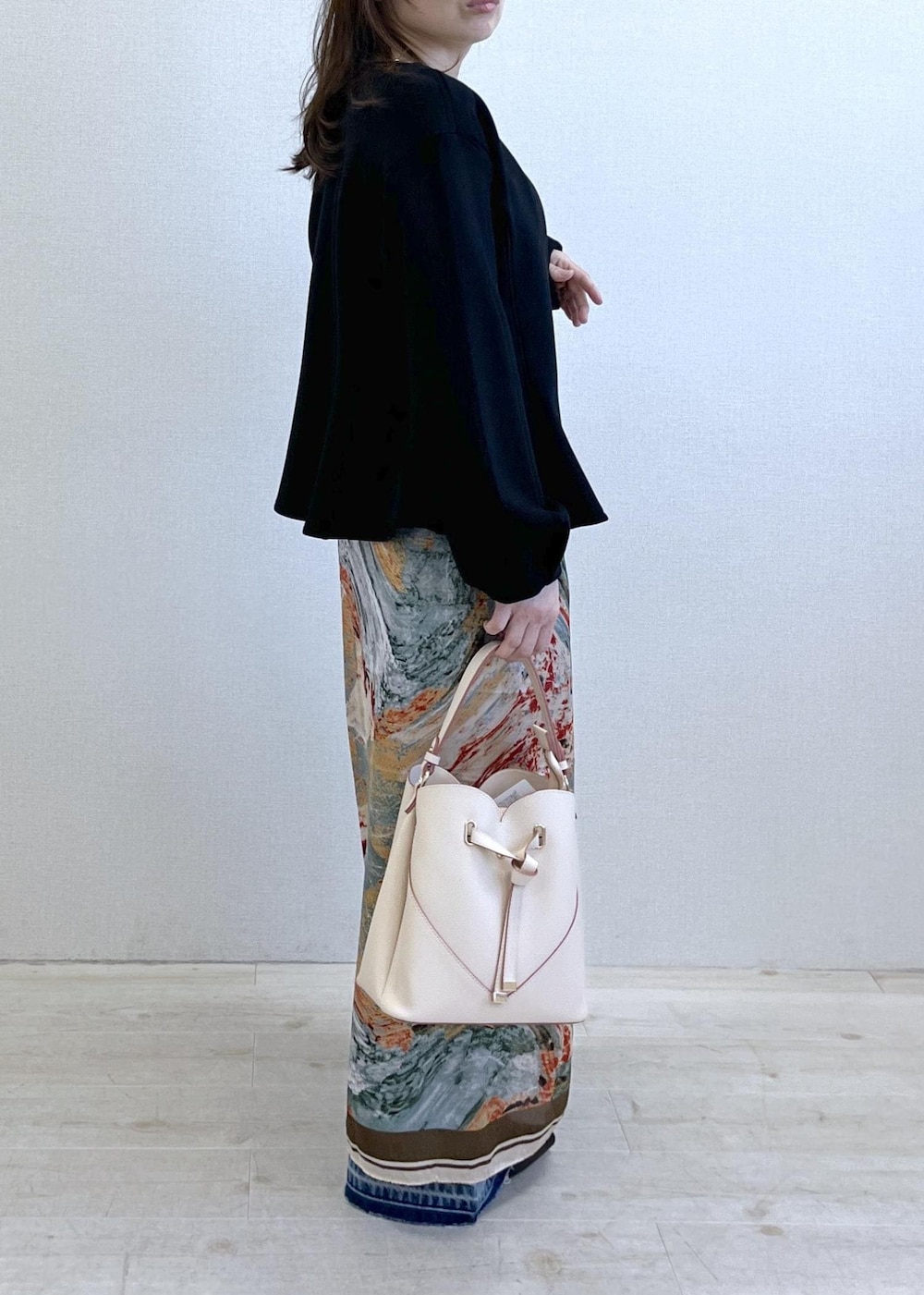 ベージュ系のショルダーバッグ、ブラック系のパンプス、ホワイト系のキャミソールを着用したレディースの春コーディネートの3枚目の写真