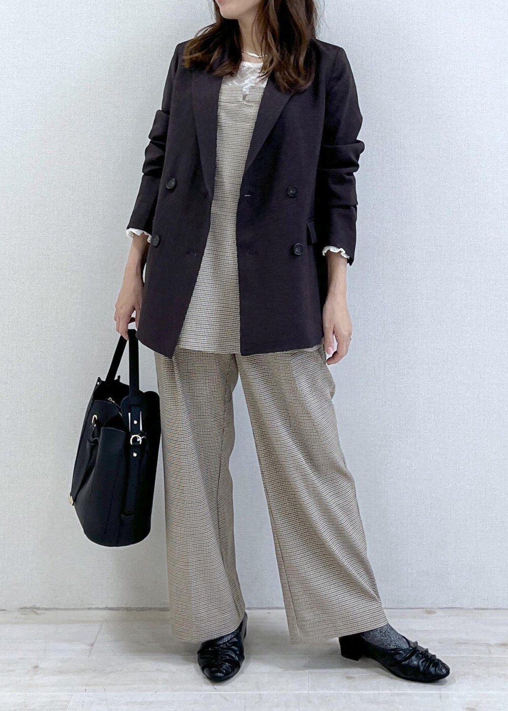 ベージュ系のスラックス、ブラウン系のテーラードジャケット、ベージュ系のキャミソールを着用したレディースの秋コーディネートの9枚目の写真