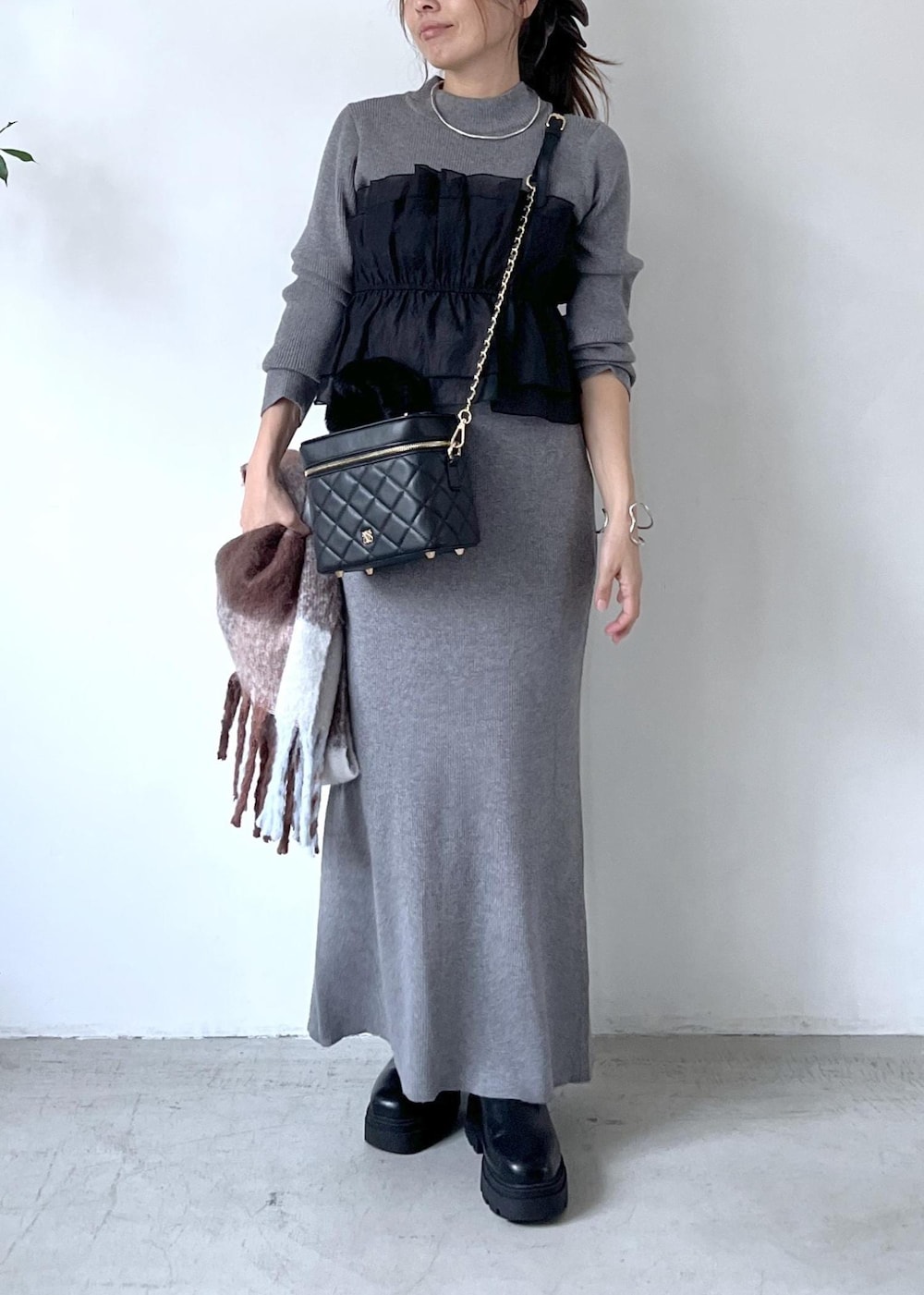 ブラック系のブーツ、グレー系のスカート、グレー系のニット/セーターを着用したレディースの秋コーディネートの9枚目の写真