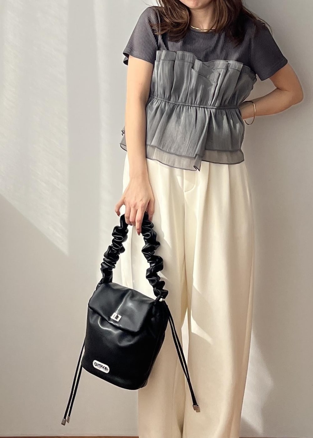 ホワイト系のスラックス、ブラック系のショルダーバッグ、ホワイト系のサンダルを着用したレディースの春コーディネートの2枚目の写真