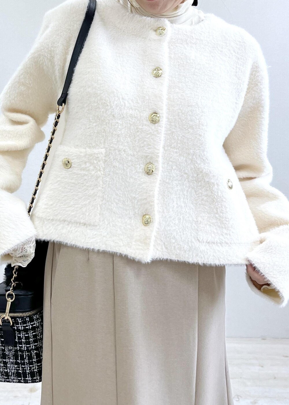 ベージュ系のスカート、ホワイト系のカーディガン/ボレロ、ホワイト系のTシャツ/カットソーを着用したレディースの秋コーディネートの7枚目の写真