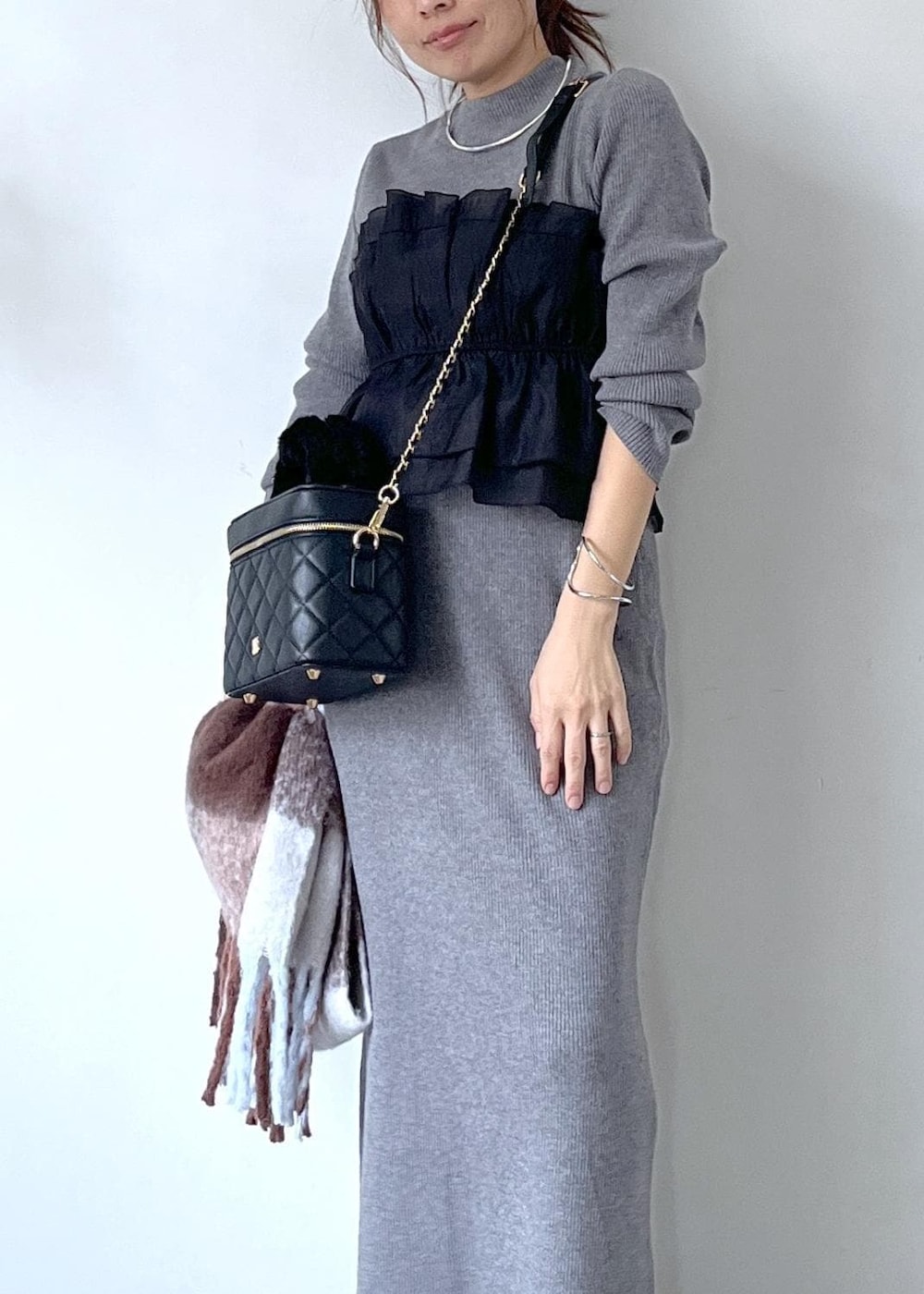 ブラック系のブーツ、グレー系のスカート、グレー系のニット/セーターを着用したレディースの秋コーディネートの2枚目の写真