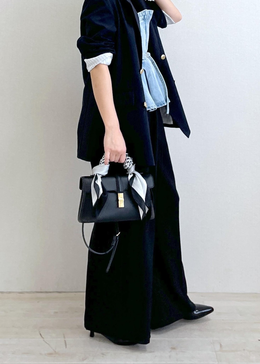 ブラック系のショルダーバッグ、ブルー系のキャミソール、ブルー系のスラックスを着用したレディースの冬コーディネートの2枚目の写真