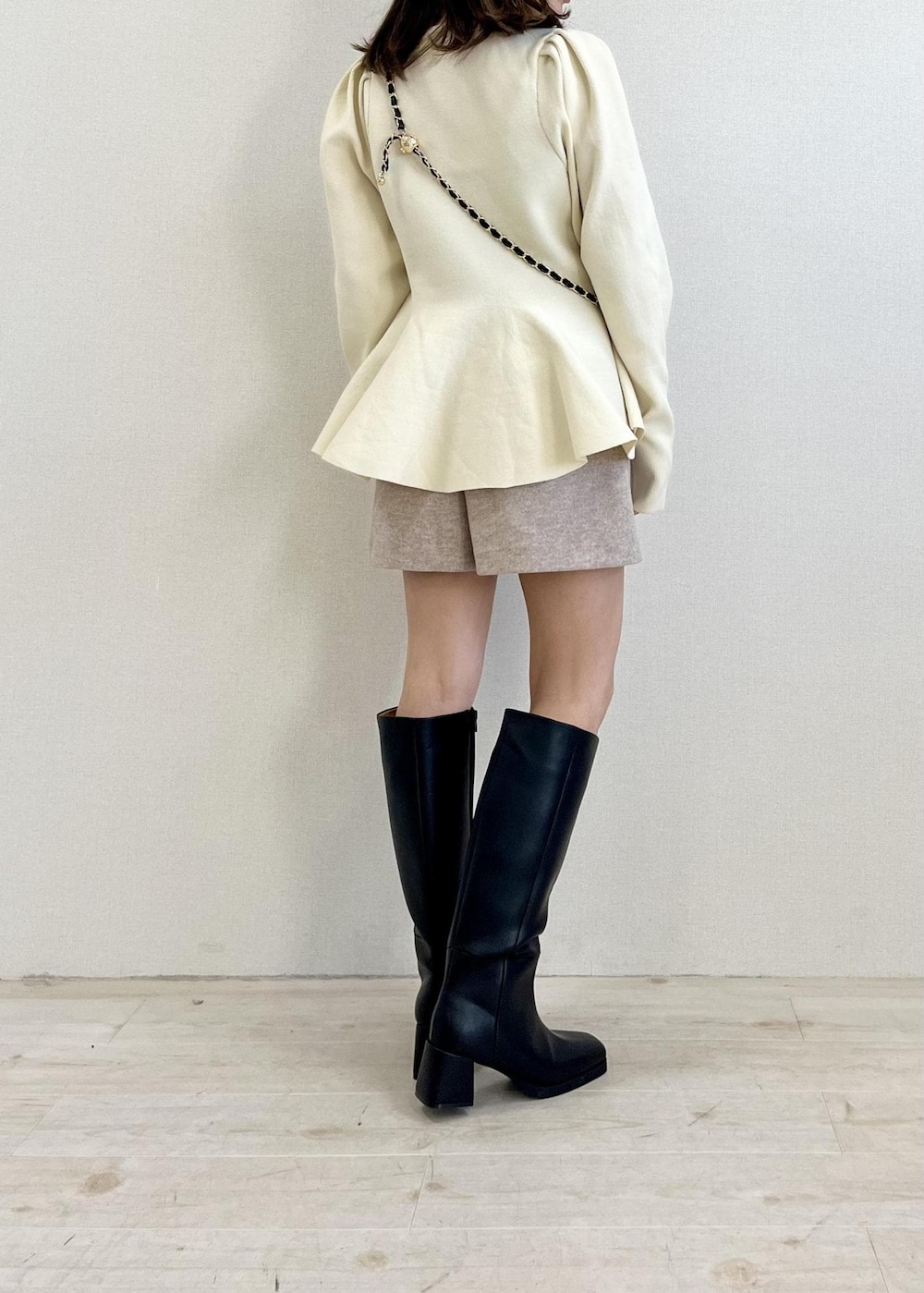 ブラック系のブーツ、ベージュ系のスラックス、ブラック系のショルダーバッグを着用したレディースの冬コーディネートの3枚目の写真