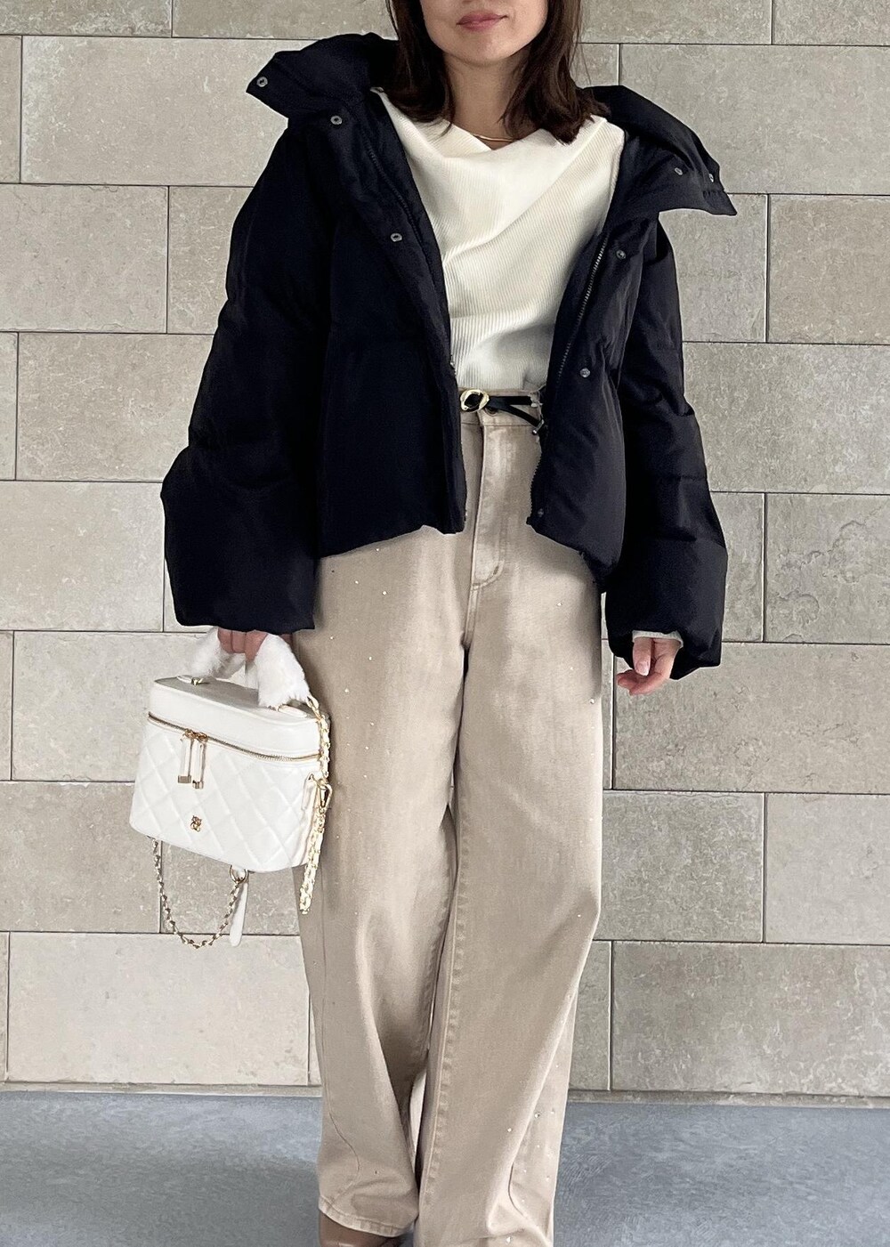 ブラック系のダウンジャケット/コート、ベージュ系のブーツ、ホワイト系のハンドバッグを着用したレディースの秋コーディネートの2枚目の写真