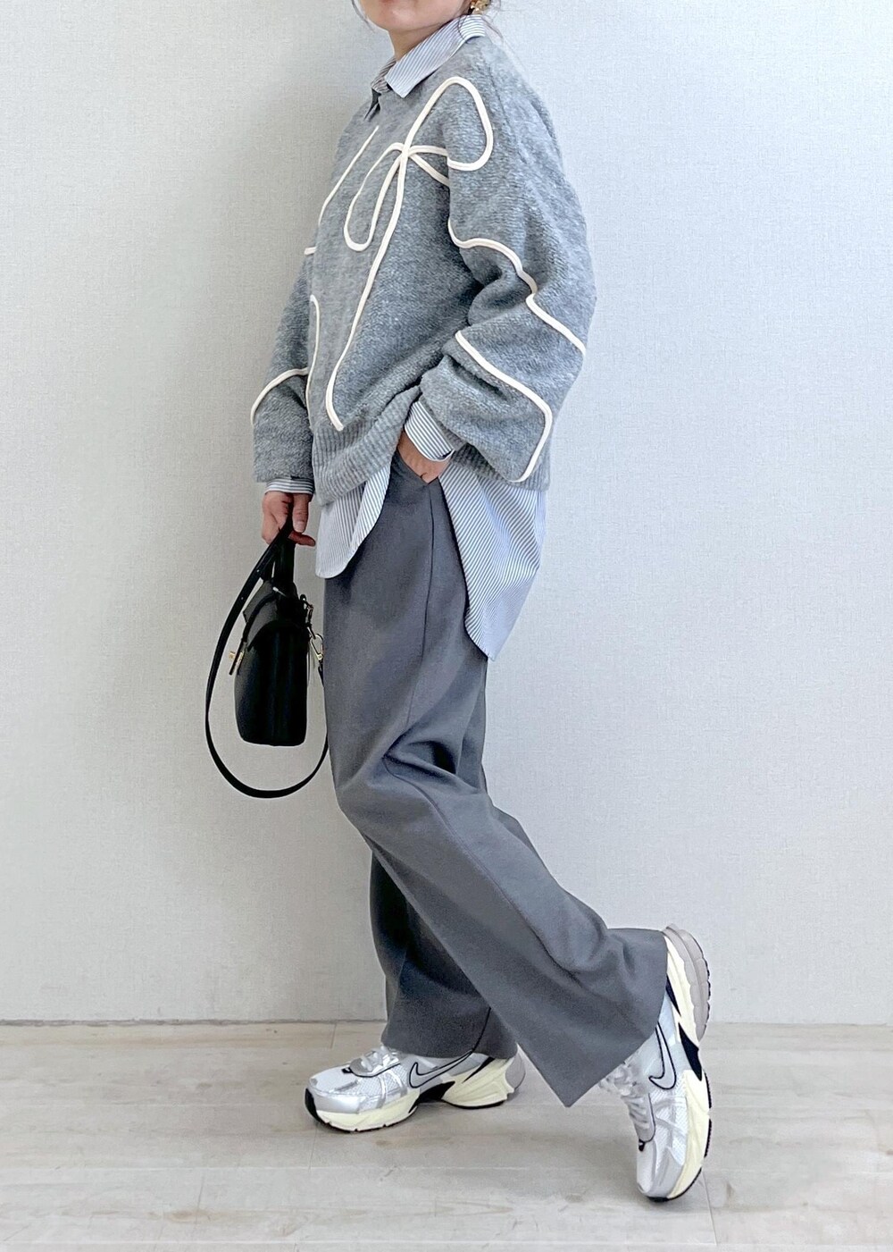 グレー系のニット/セーター、グレー系のスラックス、ブラック系のショルダーバッグを着用したレディースの冬コーディネートの2枚目の写真