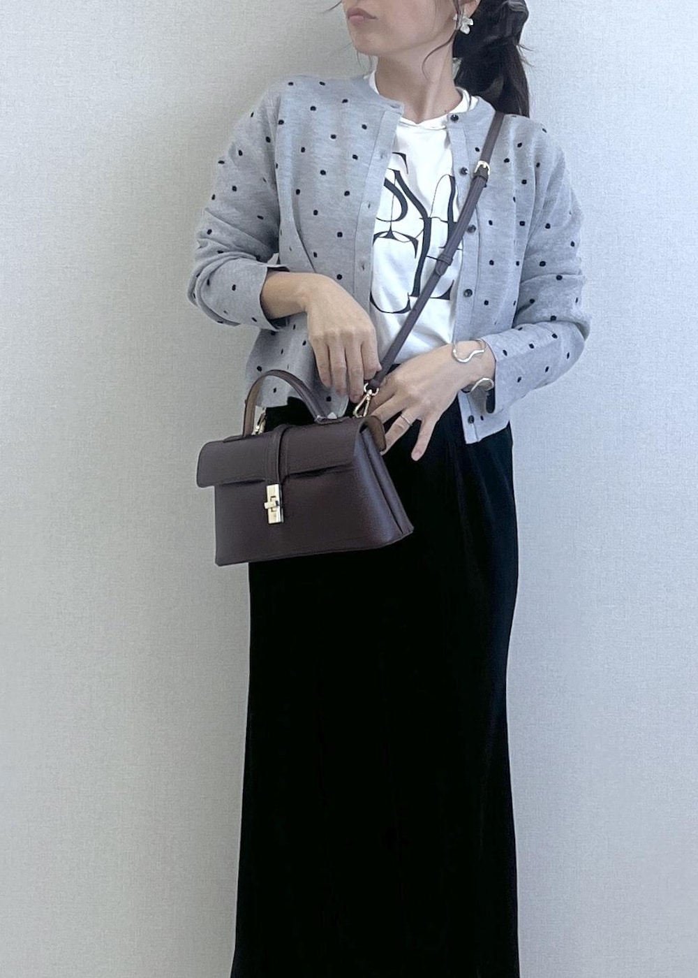 ブラウン系のショルダーバッグ、ブラック系のブーツ、ブラック系のスカートを着用したレディースの秋コーディネートの2枚目の写真