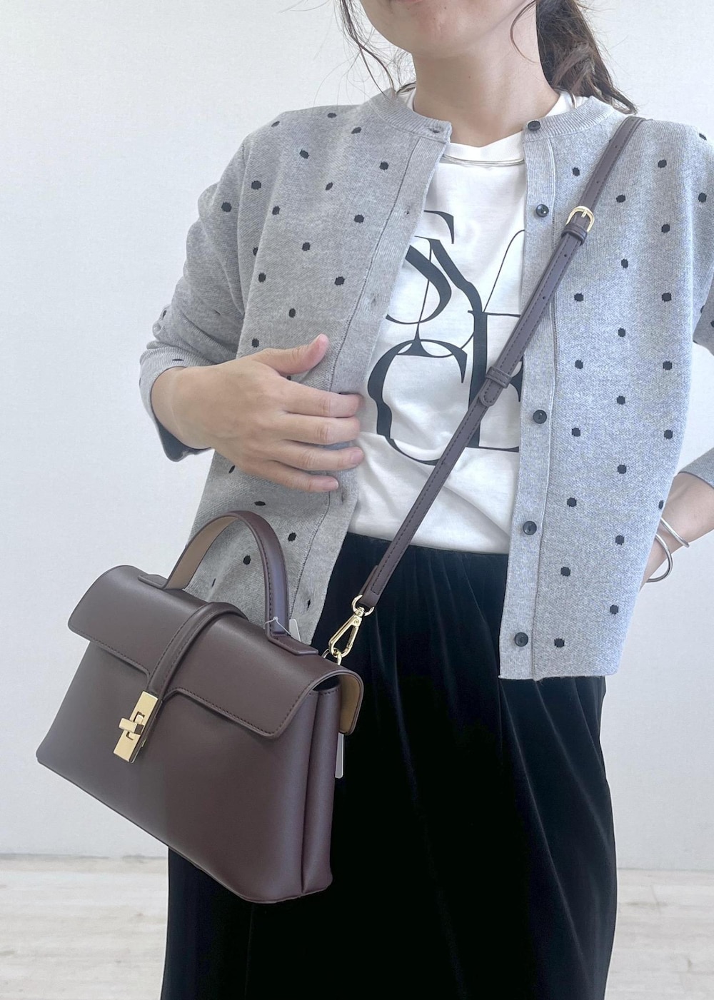 ブラウン系のショルダーバッグ、ブラック系のブーツ、ブラック系のスカートを着用したレディースの秋コーディネートの6枚目の写真