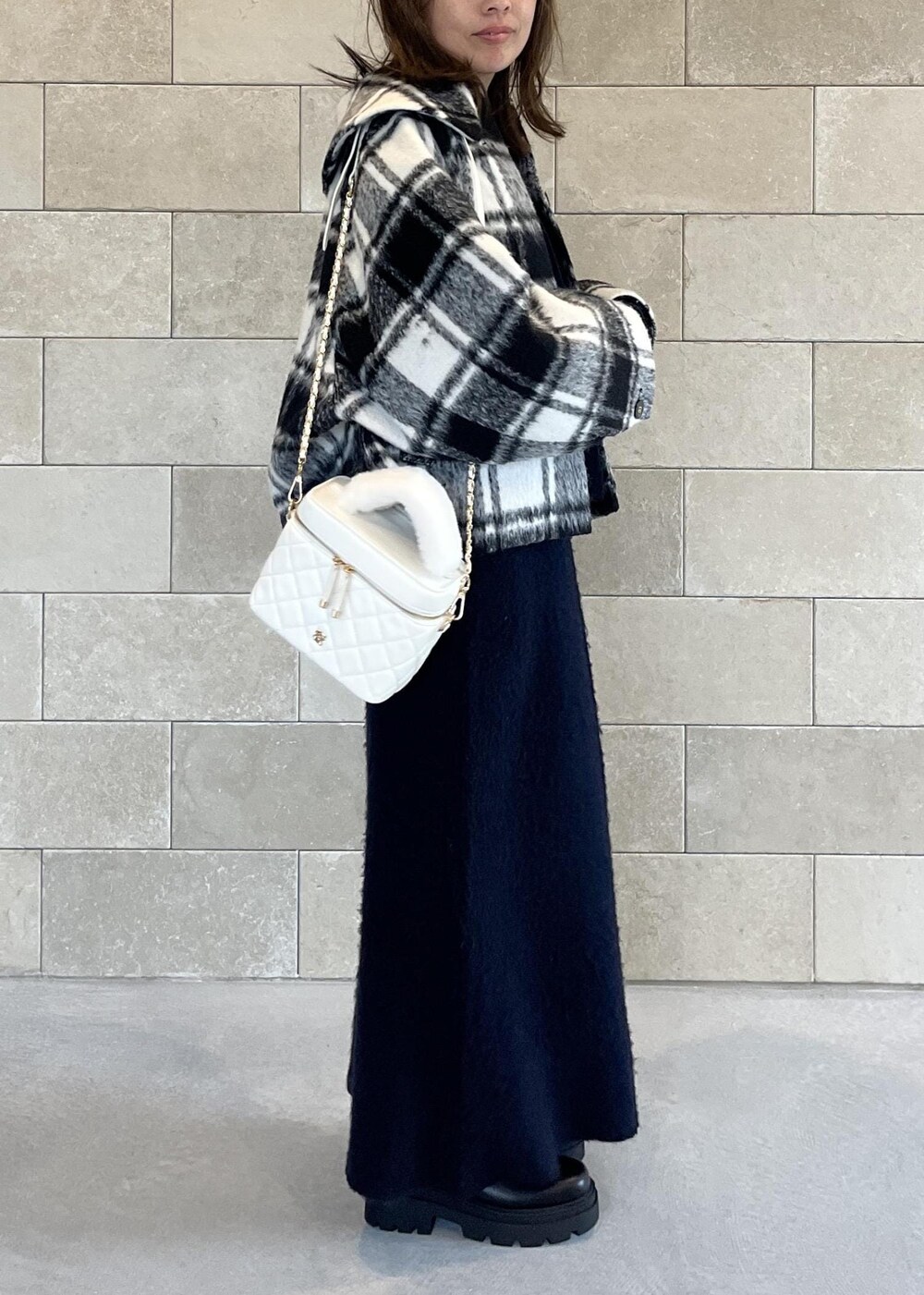 ブラック系のブーツ、ホワイト系のハンドバッグ、ブルー系のスカートを着用したレディースの秋コーディネートの4枚目の写真