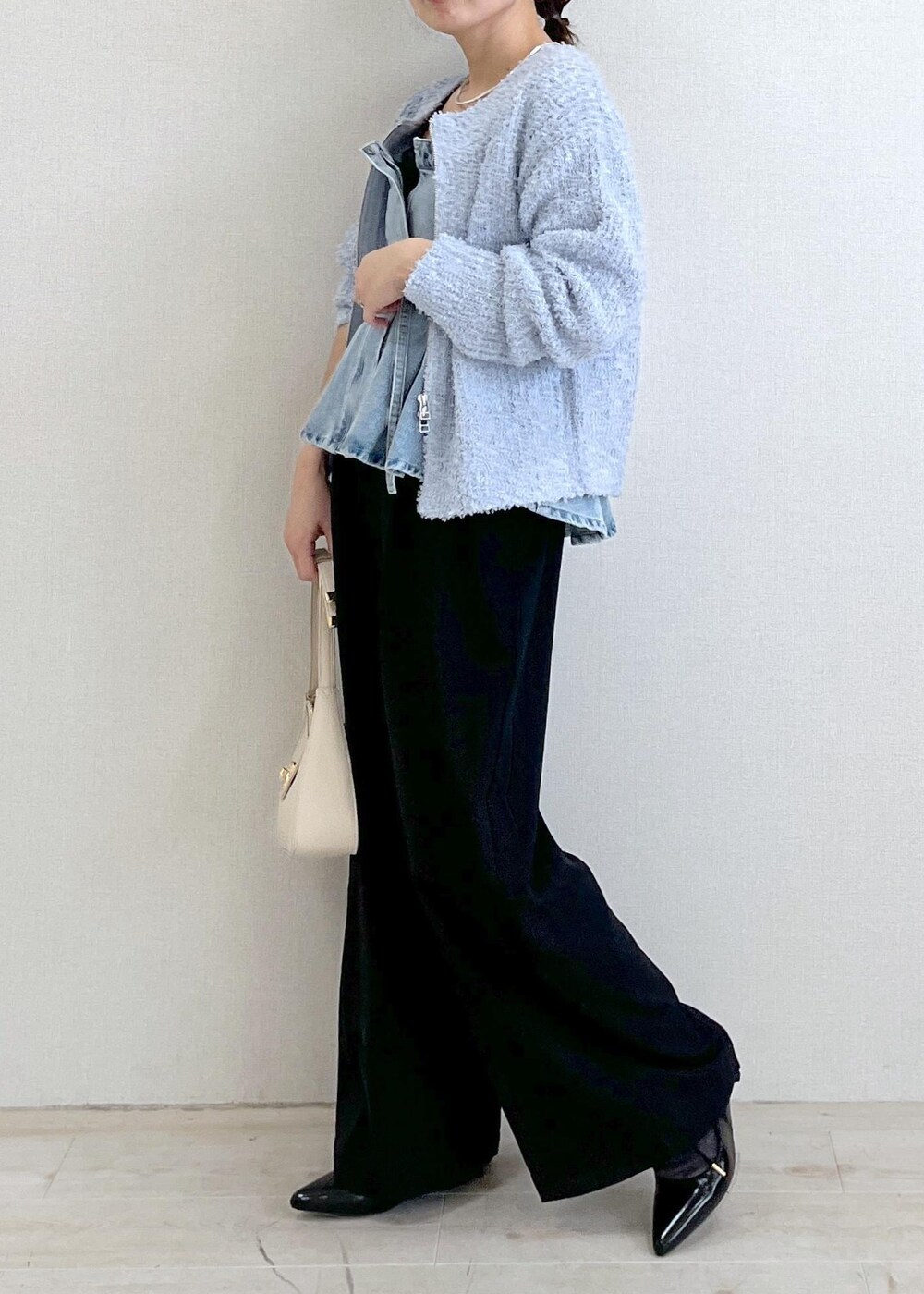 ホワイト系のハンドバッグ、ブルー系のカーディガン/ボレロ、ブラック系のサロペット/オーバーオールを着用したレディースの春コーディネートの3枚目の写真