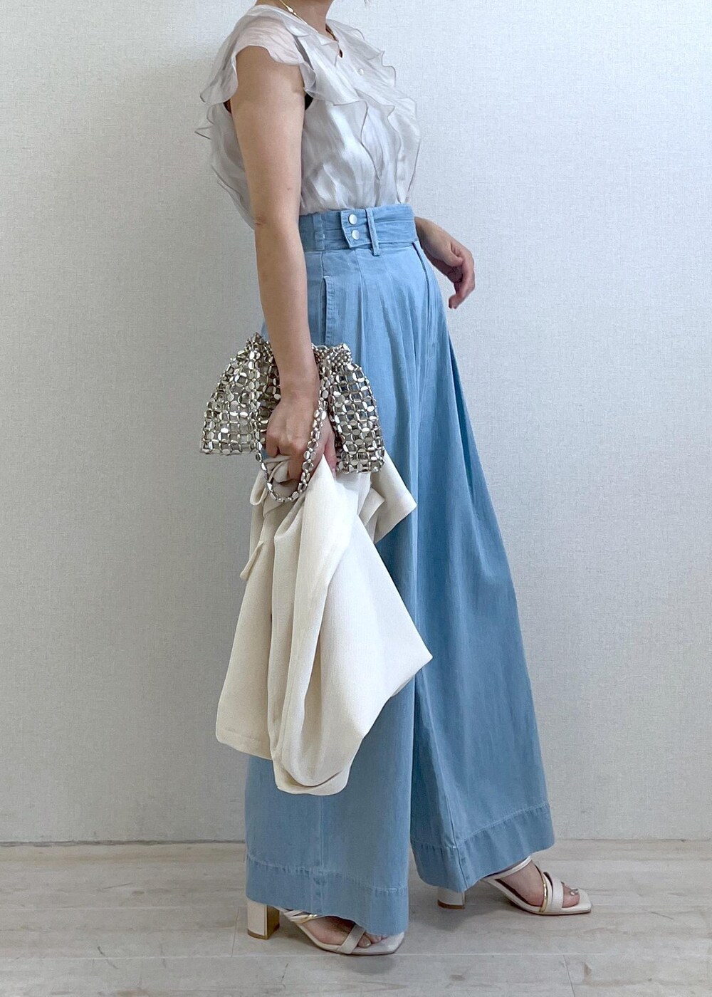 ホワイト系のサンダル、シルバー系のハンドバッグ、ブルー系のデニムパンツを着用したレディースの夏コーディネートの3枚目の写真