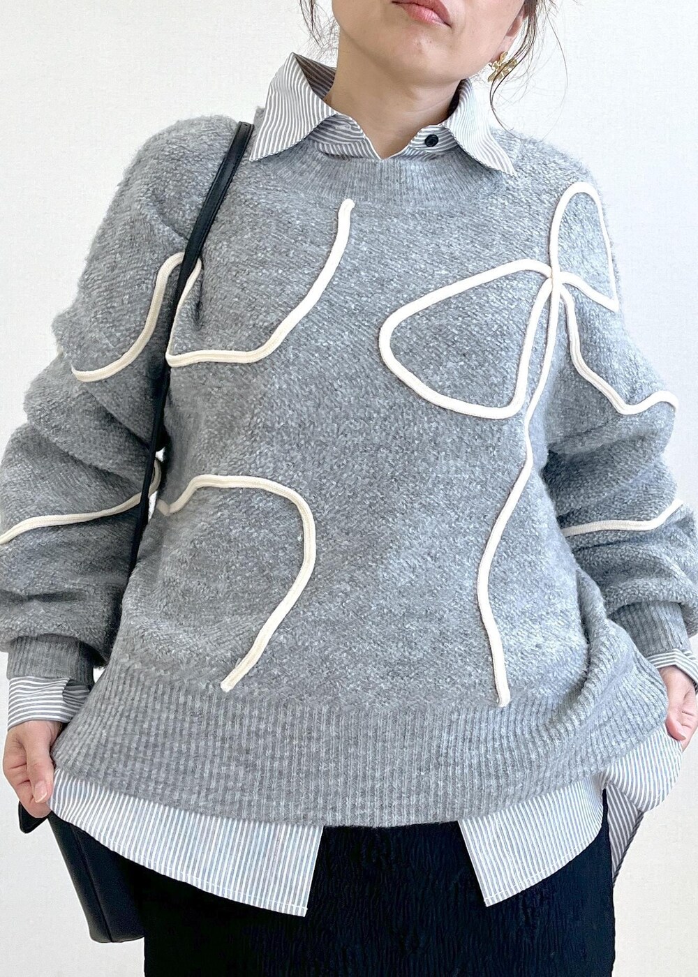 グレー系のニット/セーター、グレー系のスラックス、ブラック系のショルダーバッグを着用したレディースの冬コーディネートの6枚目の写真