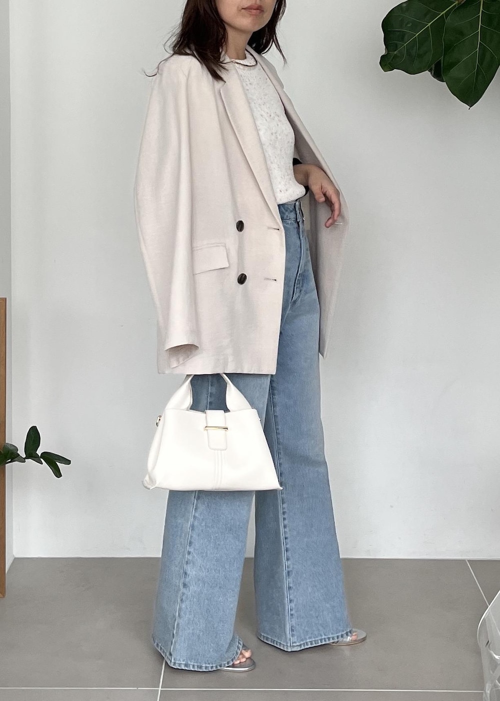 ホワイト系のテーラードジャケット、ブルー系のデニムパンツ、シルバー系のサンダルを着用したレディースの春コーディネートの3枚目の写真