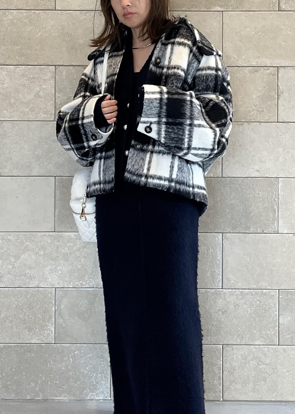 ブラック系のブーツ、ホワイト系のハンドバッグ、ブルー系のスカートを着用したレディースの秋コーディネートの3枚目の写真