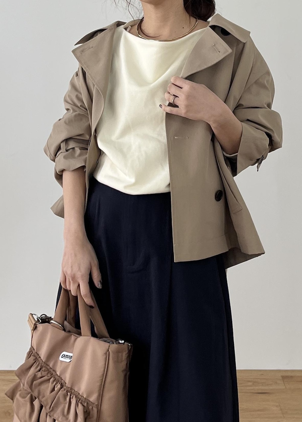 ブラック系のパンプス、ベージュ系のトートバッグ、ベージュ系のトレンチコートを着用したレディースの冬コーディネートの2枚目の写真