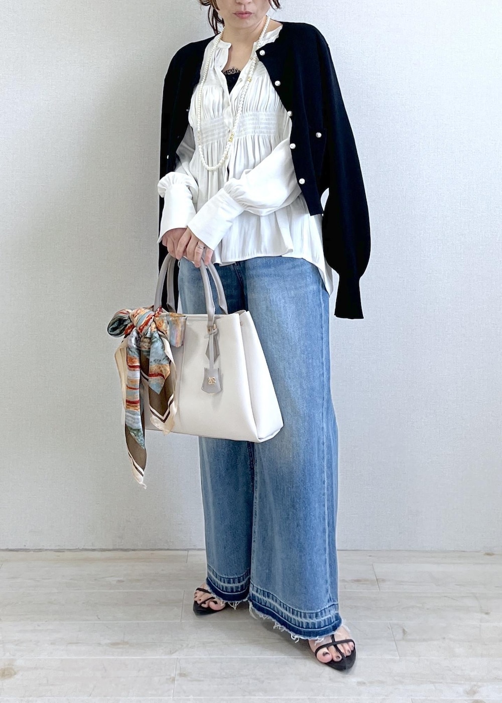 ブラック系のキャミソール、ブルー系のデニムパンツ、ブラック系のカーディガン/ボレロを着用したレディースの春コーディネートの2枚目の写真