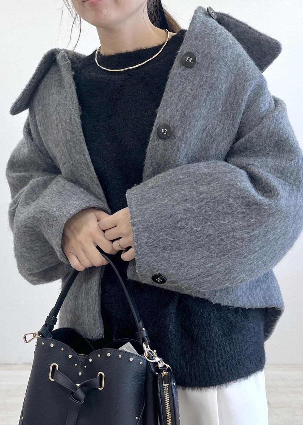 グレー系のブルゾン、ホワイト系のスラックス、ブラック系のニット/セーターを着用したレディースの冬コーディネートの5枚目の写真