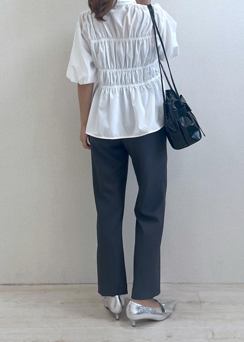 シルバー系のパンプス、ブラック系のショルダーバッグ、グレー系のスラックスを着用したレディースの秋コーディネートの4枚目の写真