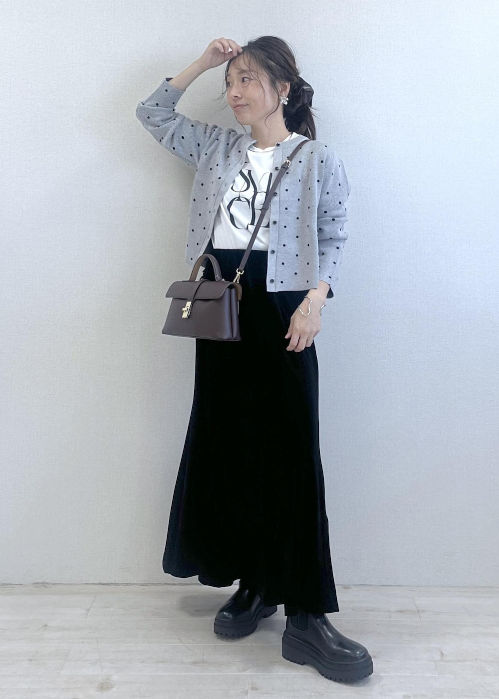 ブラウン系のショルダーバッグ、ブラック系のブーツ、ブラック系のスカートを着用したレディースの秋コーディネートの10枚目の写真