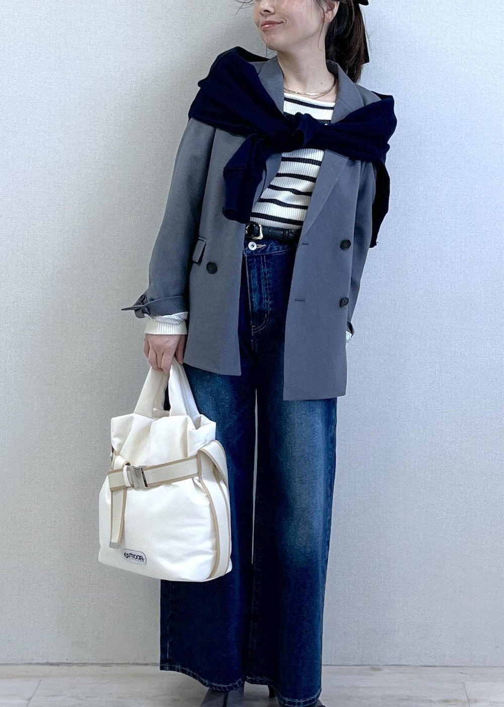 グレー系のテーラードジャケット、ブルー系のデニムパンツ、ホワイト系のニット/セーターを着用したレディースの冬コーディネートの3枚目の写真