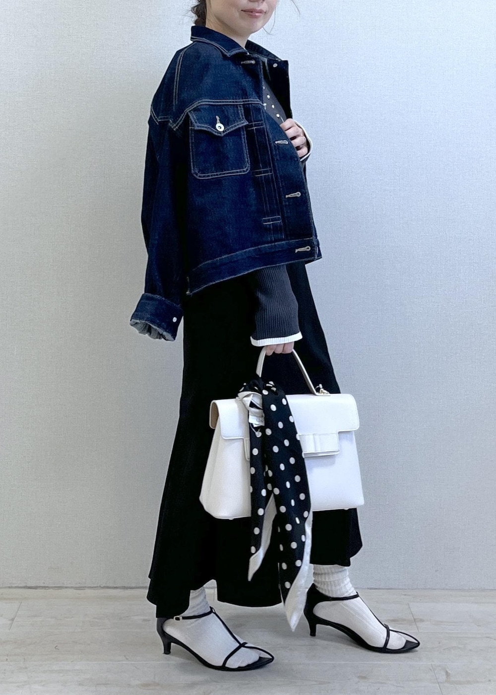 ブルー系のデニムジャケット、ブラック系のスカート、グレー系のニット/セーターを着用したレディースの冬コーディネートの3枚目の写真