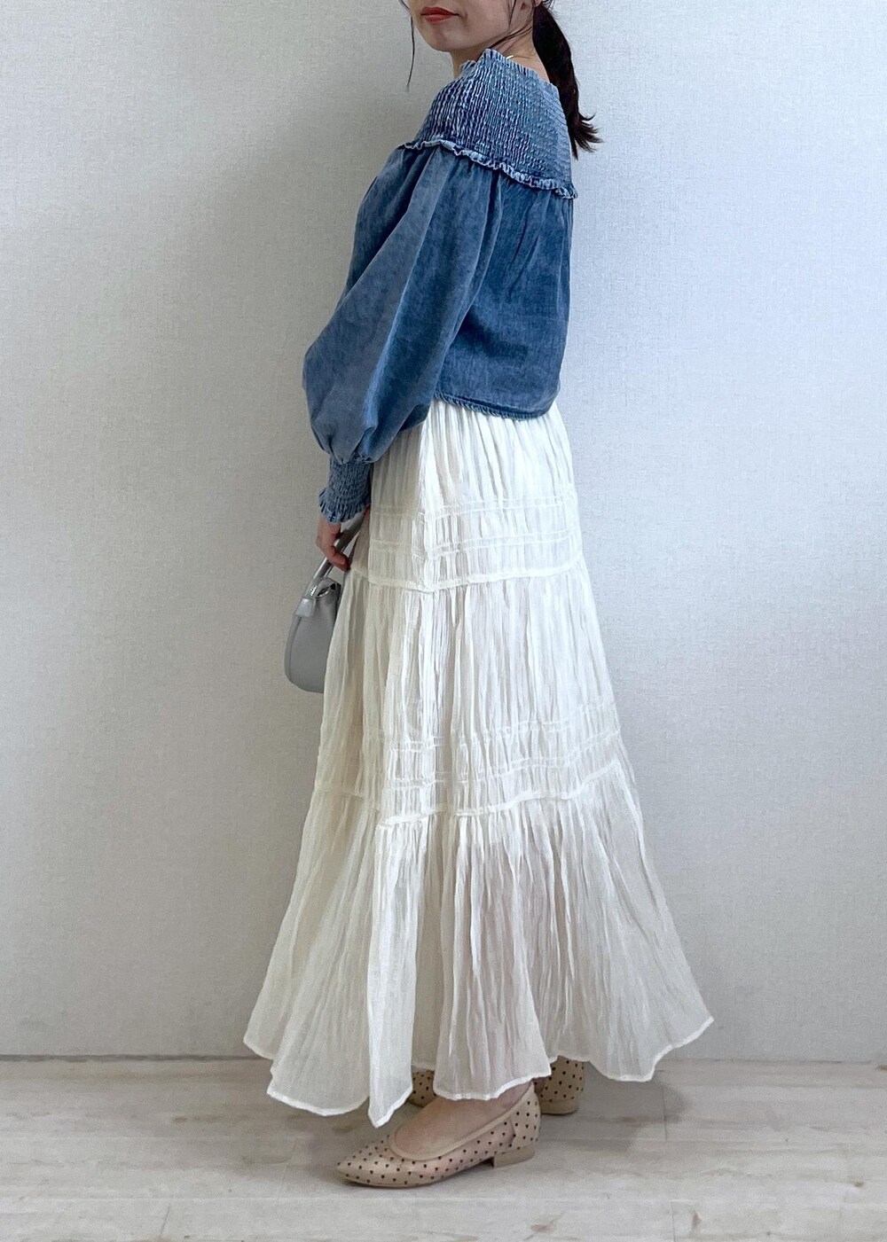 ブルー系のシャツ/ブラウス、ベージュ系のパンプス、シルバー系のショルダーバッグを着用したレディースの春コーディネートの2枚目の写真